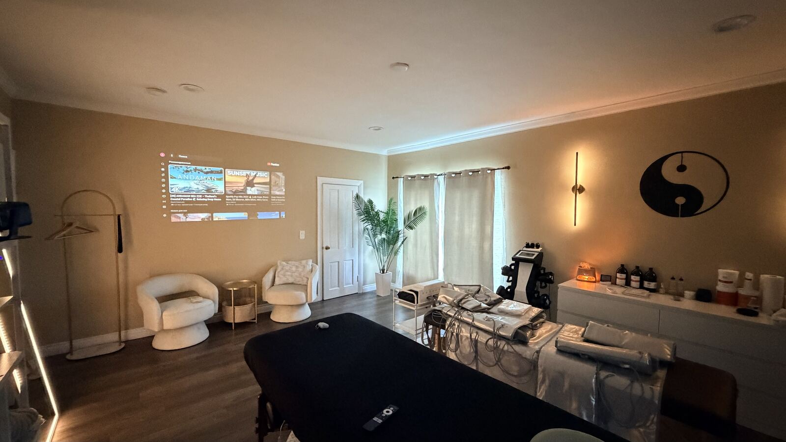 Treatment room with massage table, armchairs and warm wall lights