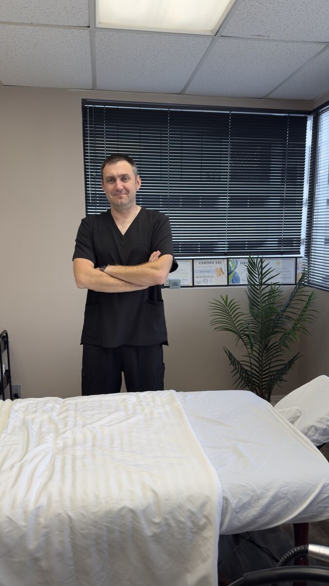 Yuriy, licensed specialist, standing by a massage table